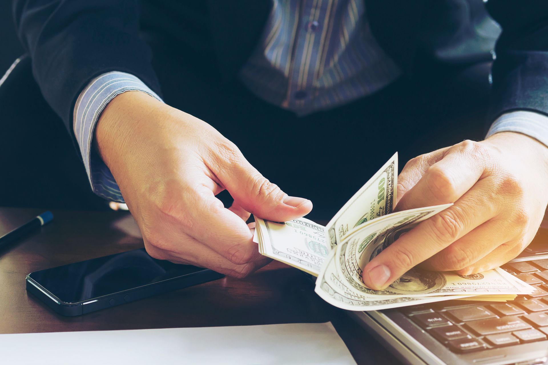 Un hombre está sentado en un escritorio contando dinero.
