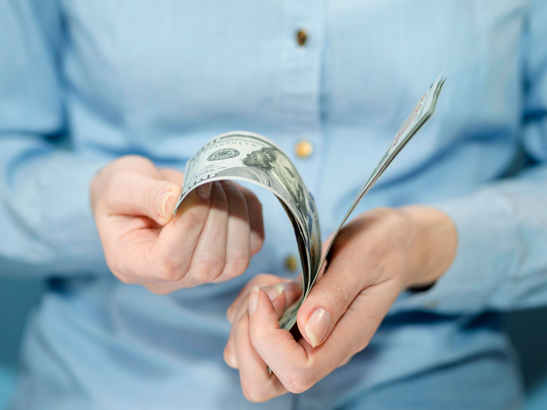 Una mujer sostiene un montón de dinero en sus manos.