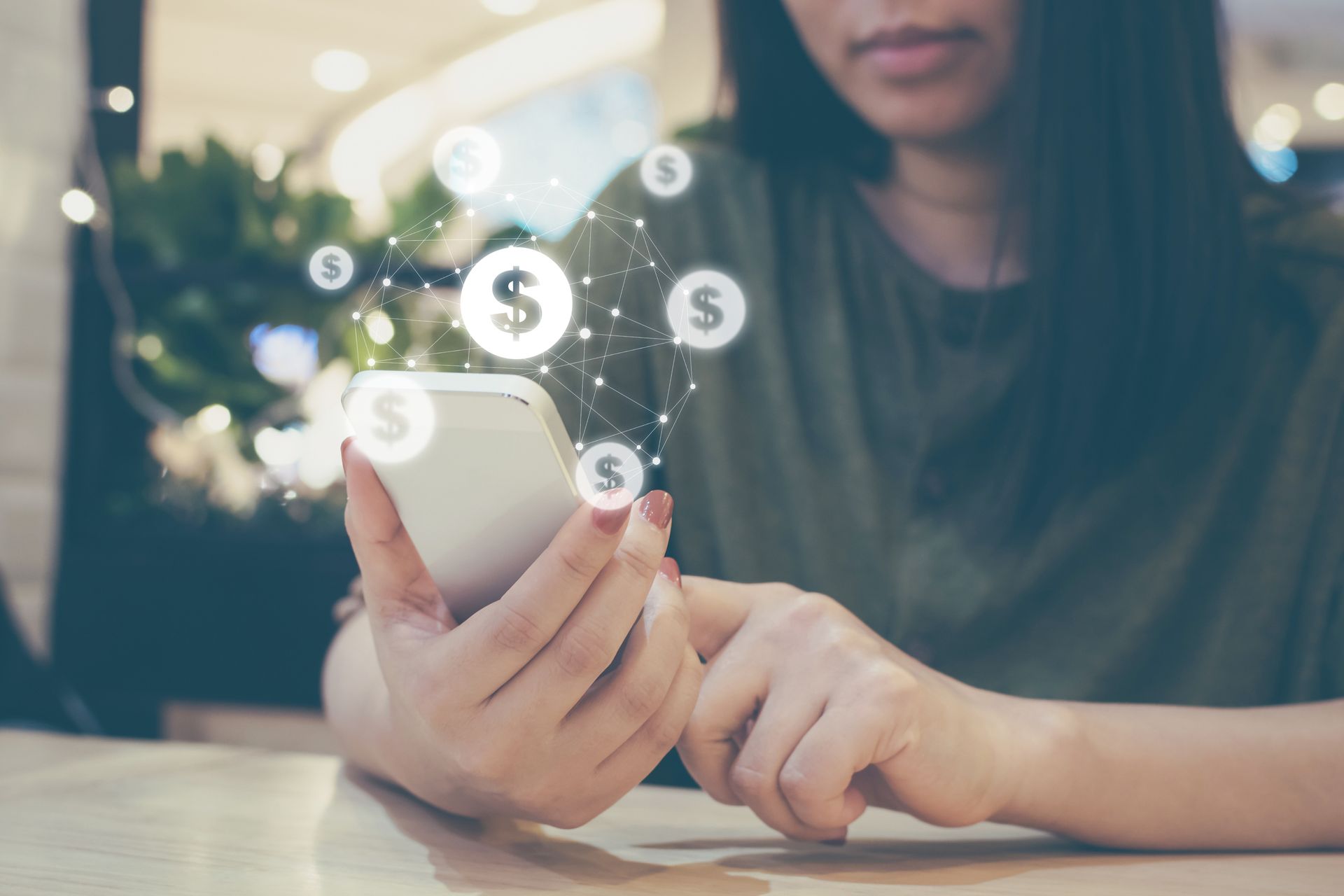 Una mujer está sentada en una mesa usando un teléfono celular.