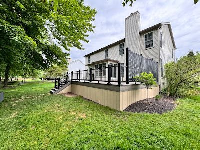 A large house with a large deck and stairs in the backyard.