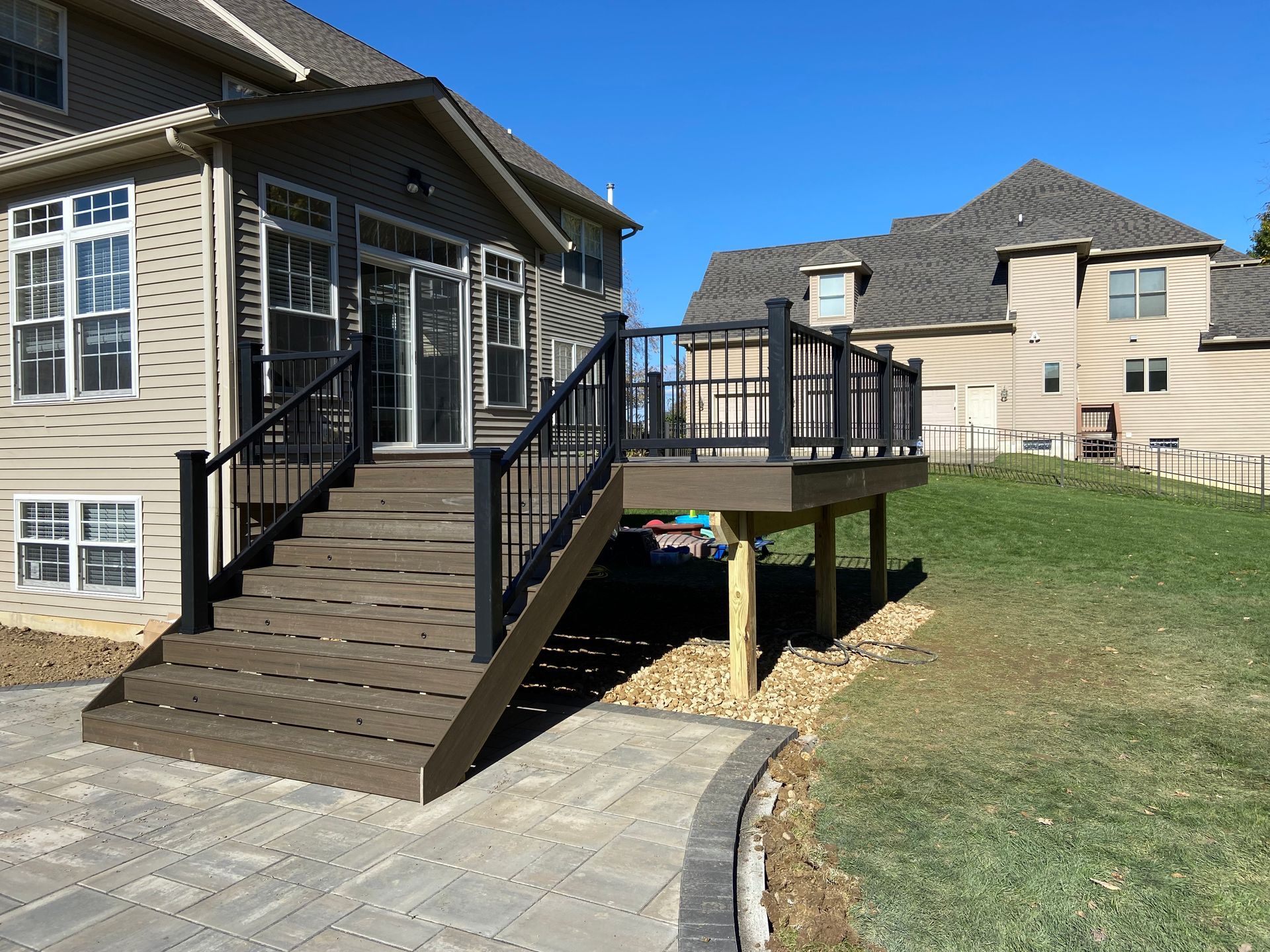 A deck with stairs leading up to it is in front of a house.