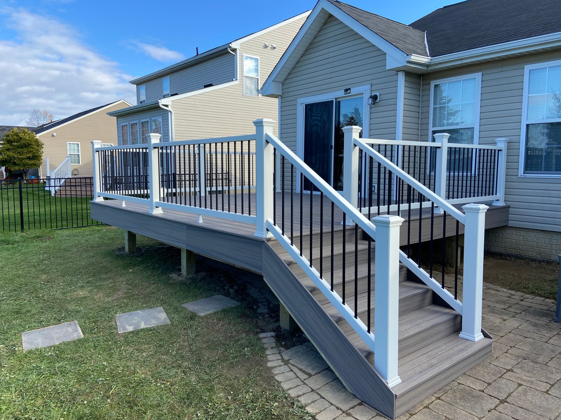 A deck with stairs leading up to the back of a house.