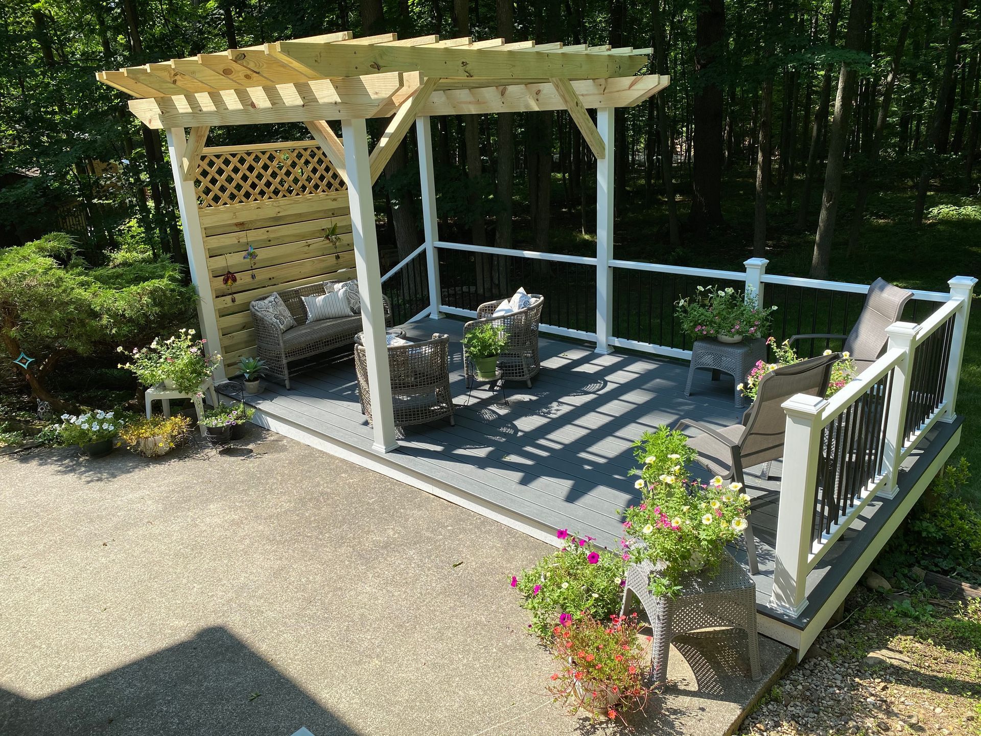 A wooden pergola is sitting on top of a patio with chairs and a couch.