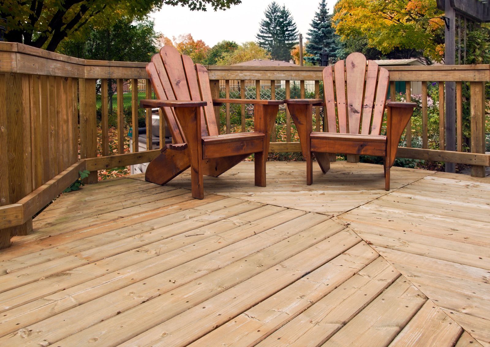 Two wooden chairs are sitting on a wooden deck.