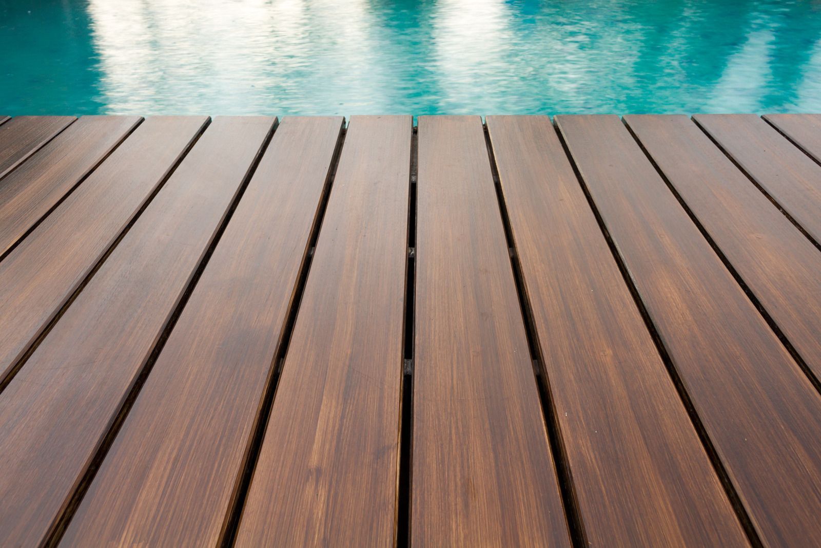 Wooden deck leading to a turquoise pool.