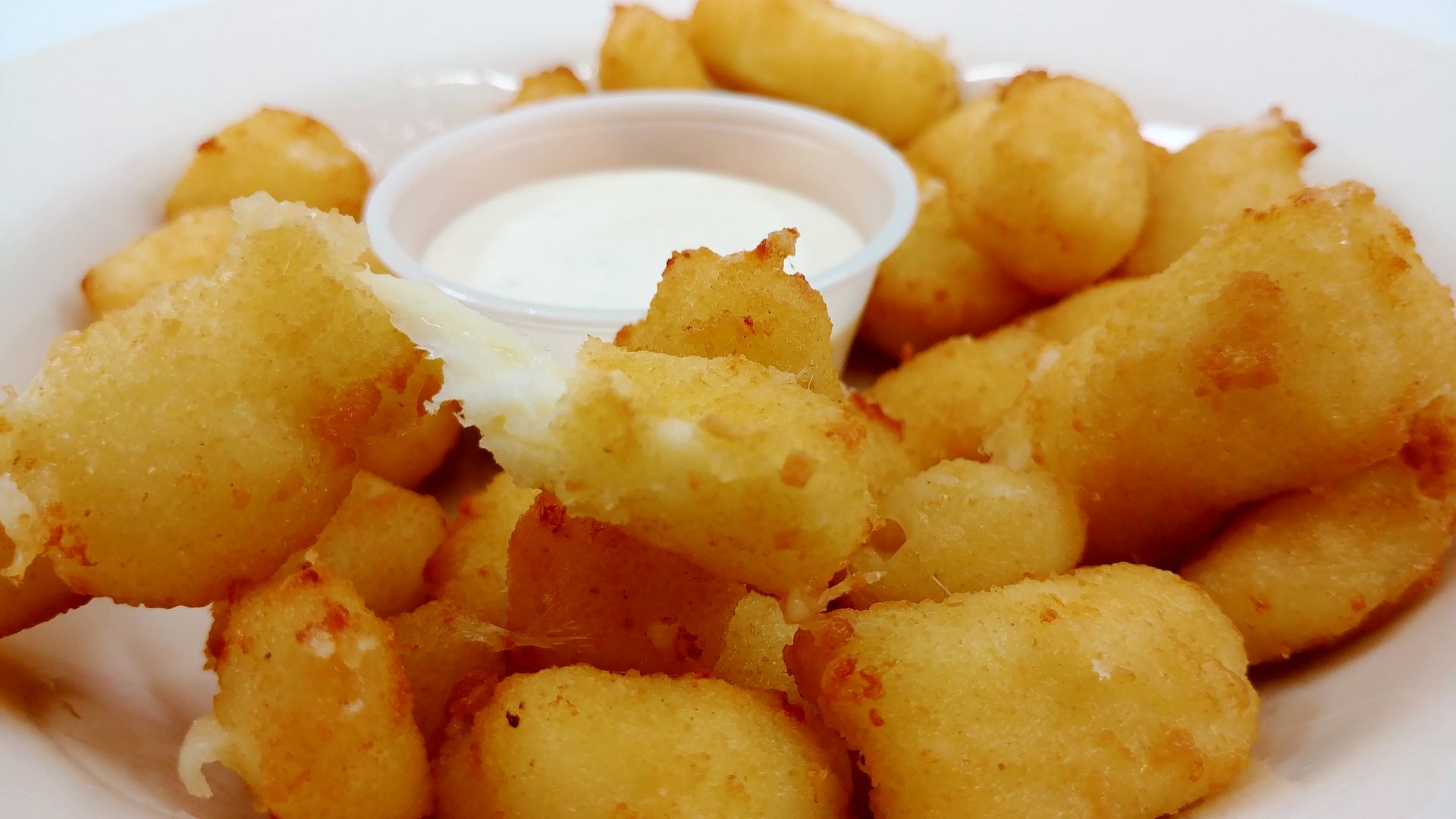 A close up of a plate of fried food with a dipping sauce.