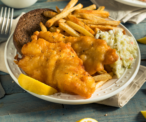 A white plate topped with fish and french fries and coleslaw.