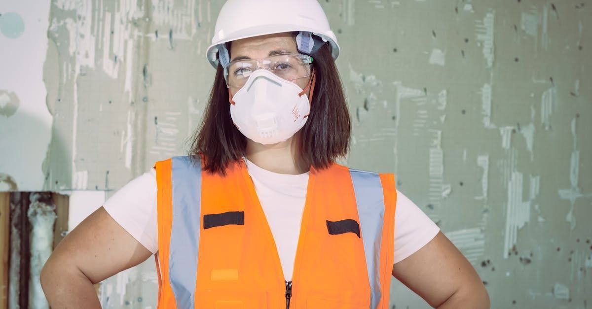 A woman wearing a hard hat and safety vest is wearing a mask.