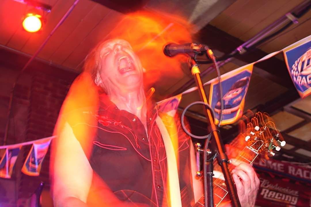 A man singing into a microphone while playing a guitar