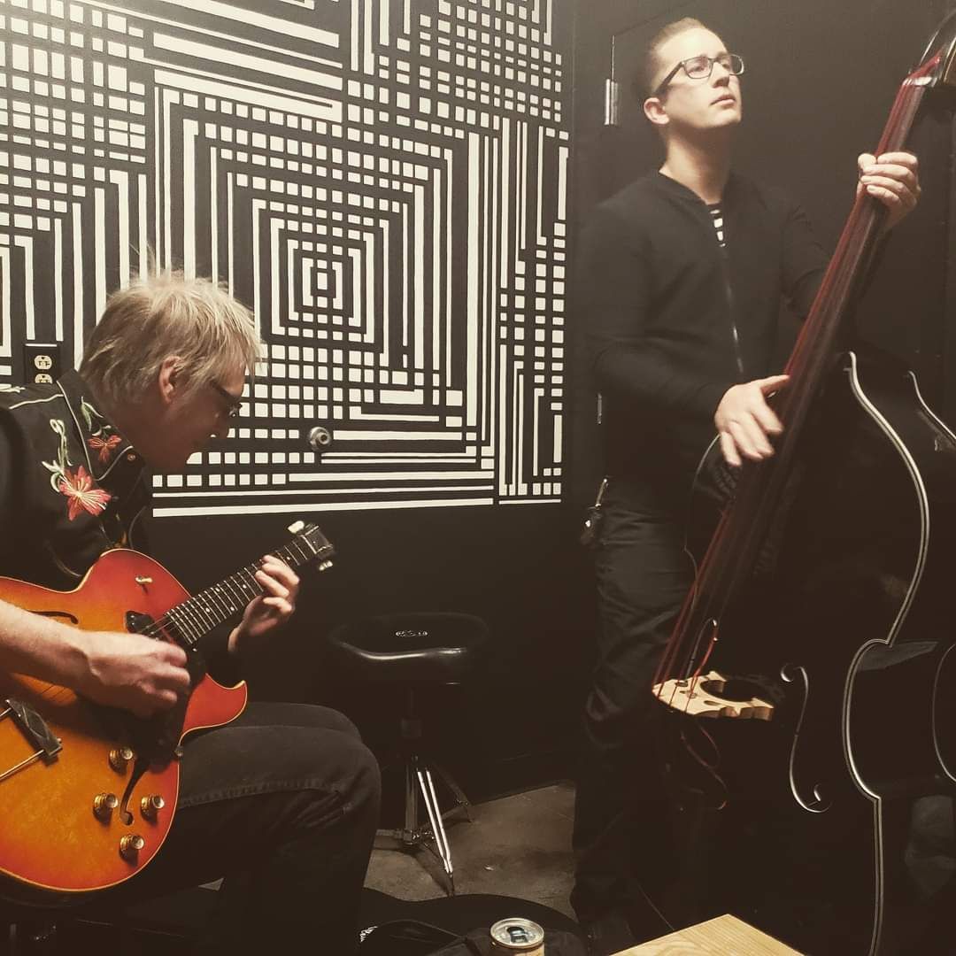 A man playing a guitar next to another man playing a double bass