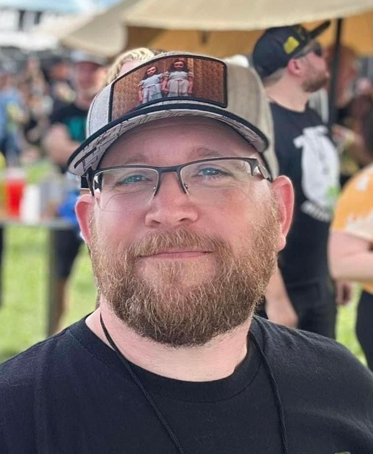 A man with a beard and glasses is wearing a hat and sunglasses.