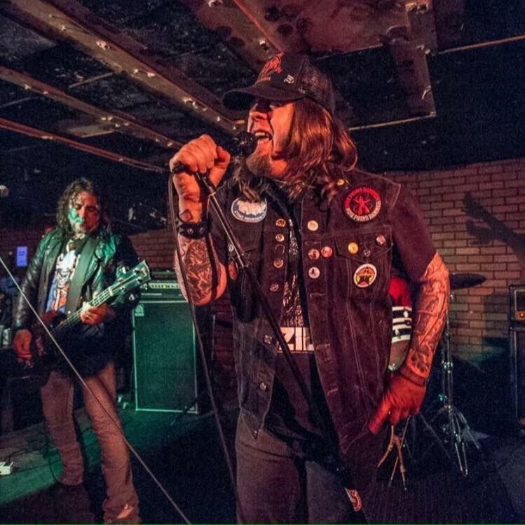 A man singing into a microphone while another man plays a guitar