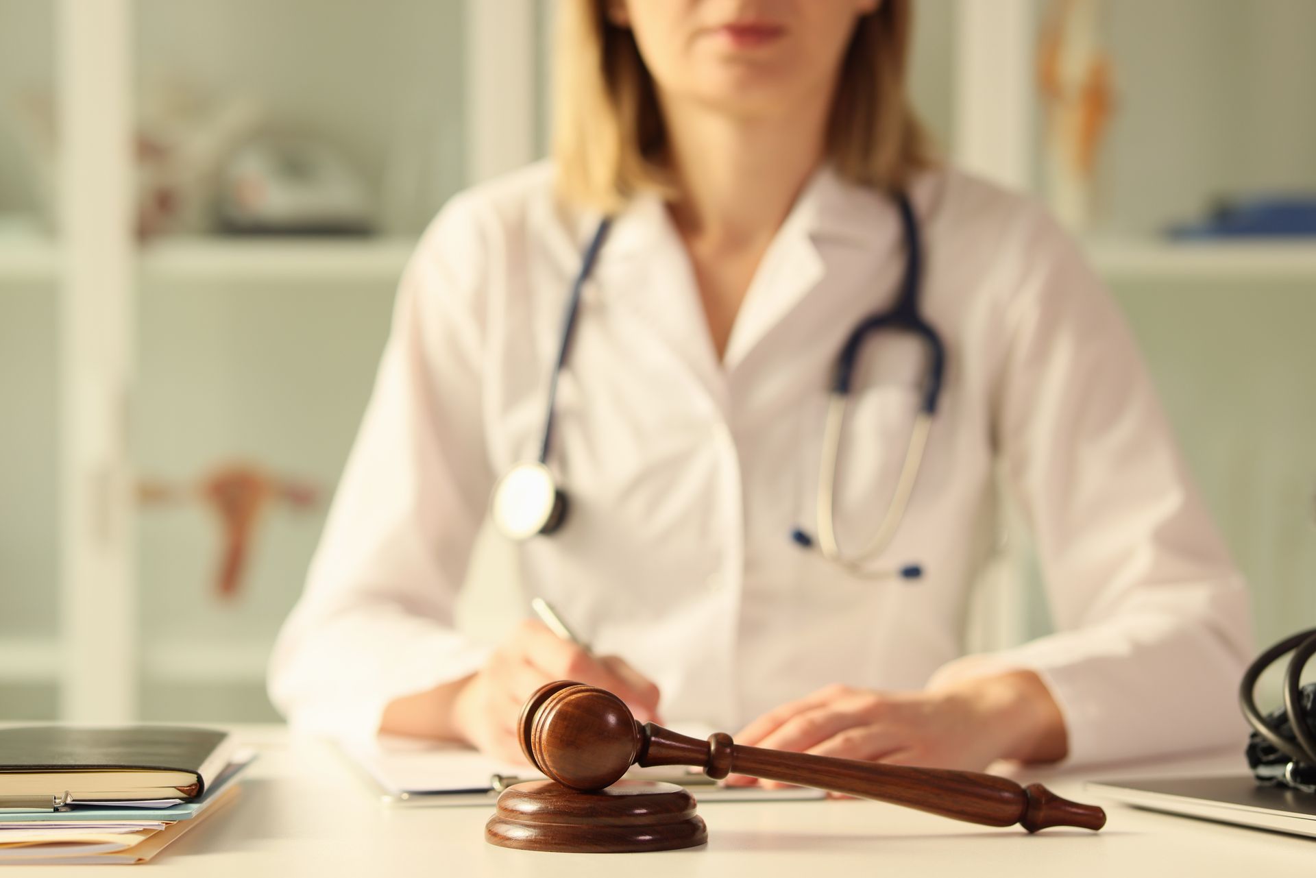 A doctor is sitting at a desk with a judge 's gavel in front of her.