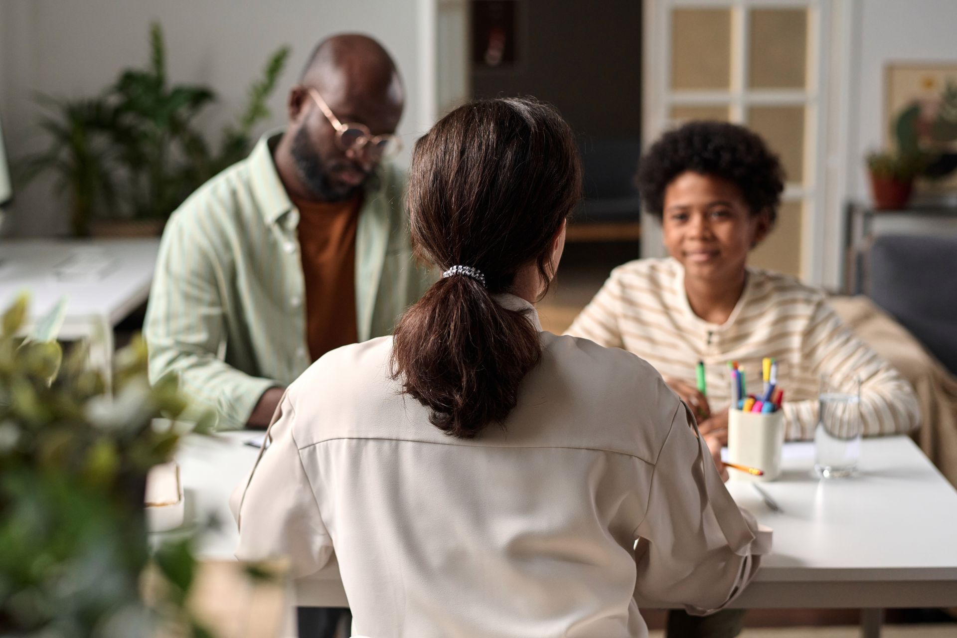 A woman is sitting at a table talking to a man and woman.