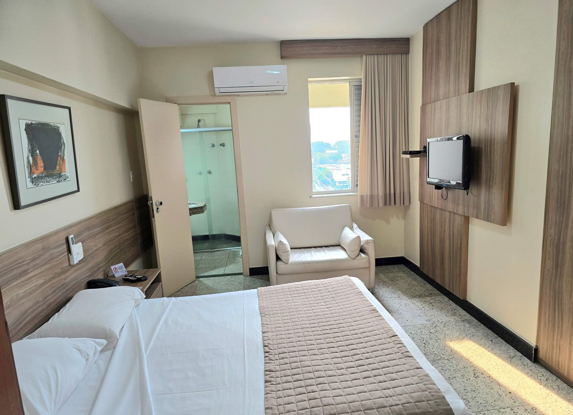 Um quarto de hotel com uma cama, cadeira e televisão.