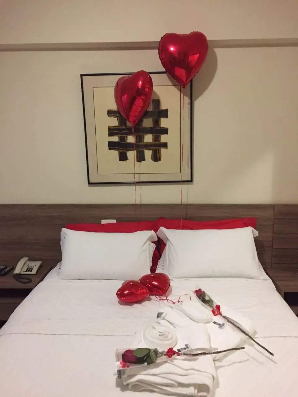 Uma cama em um quarto de hotel com balões em forma de coração