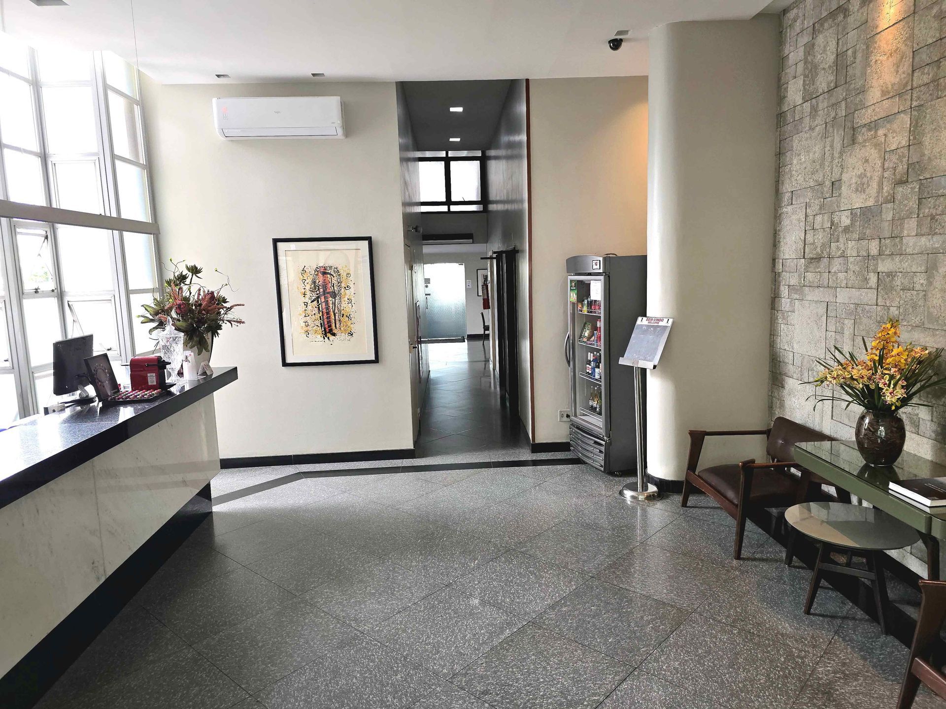 Um lobby de hotel com uma mesa, cadeiras e flores.