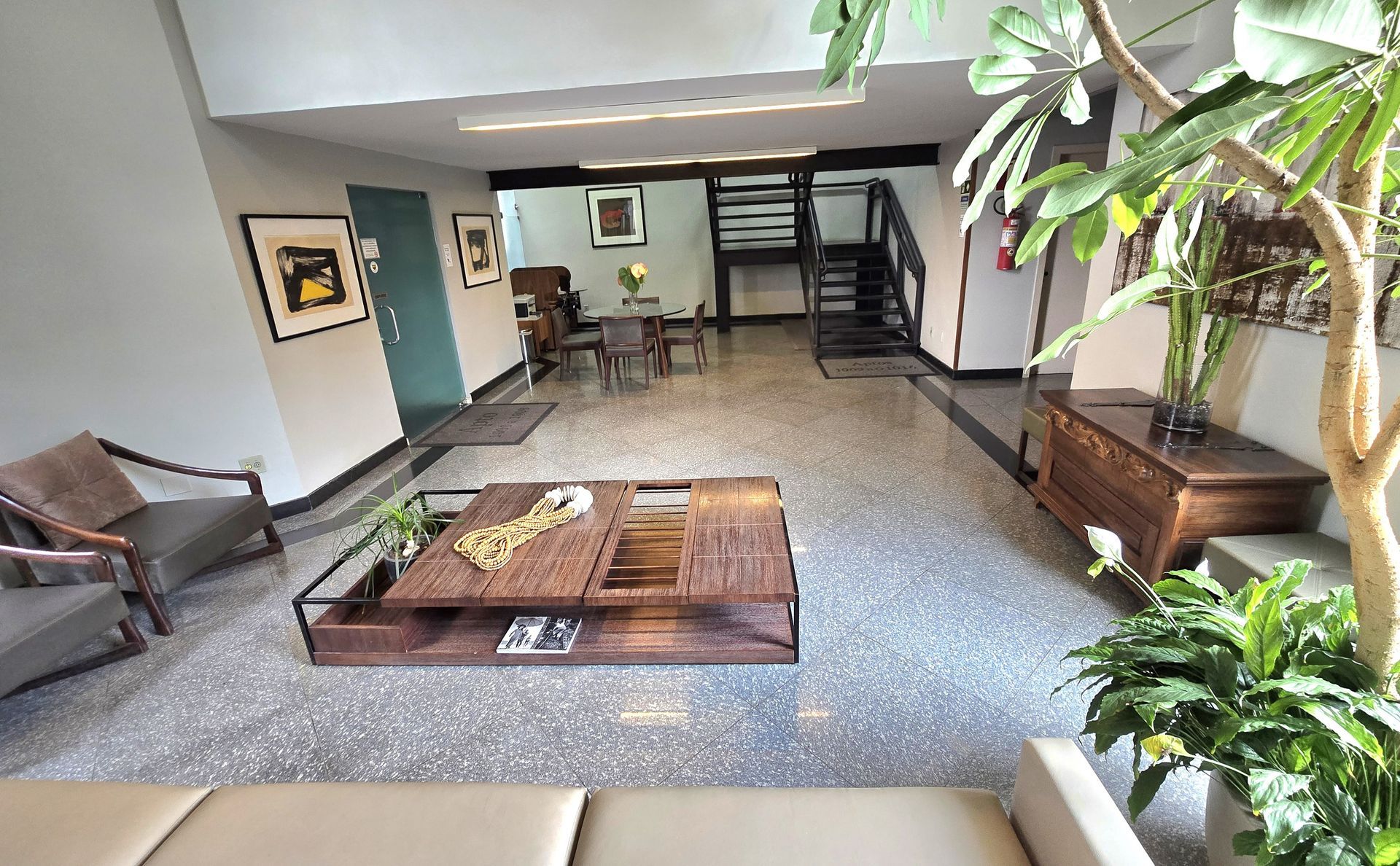 Uma sala de estar com um sofá, cadeiras, uma mesa e uma árvore.