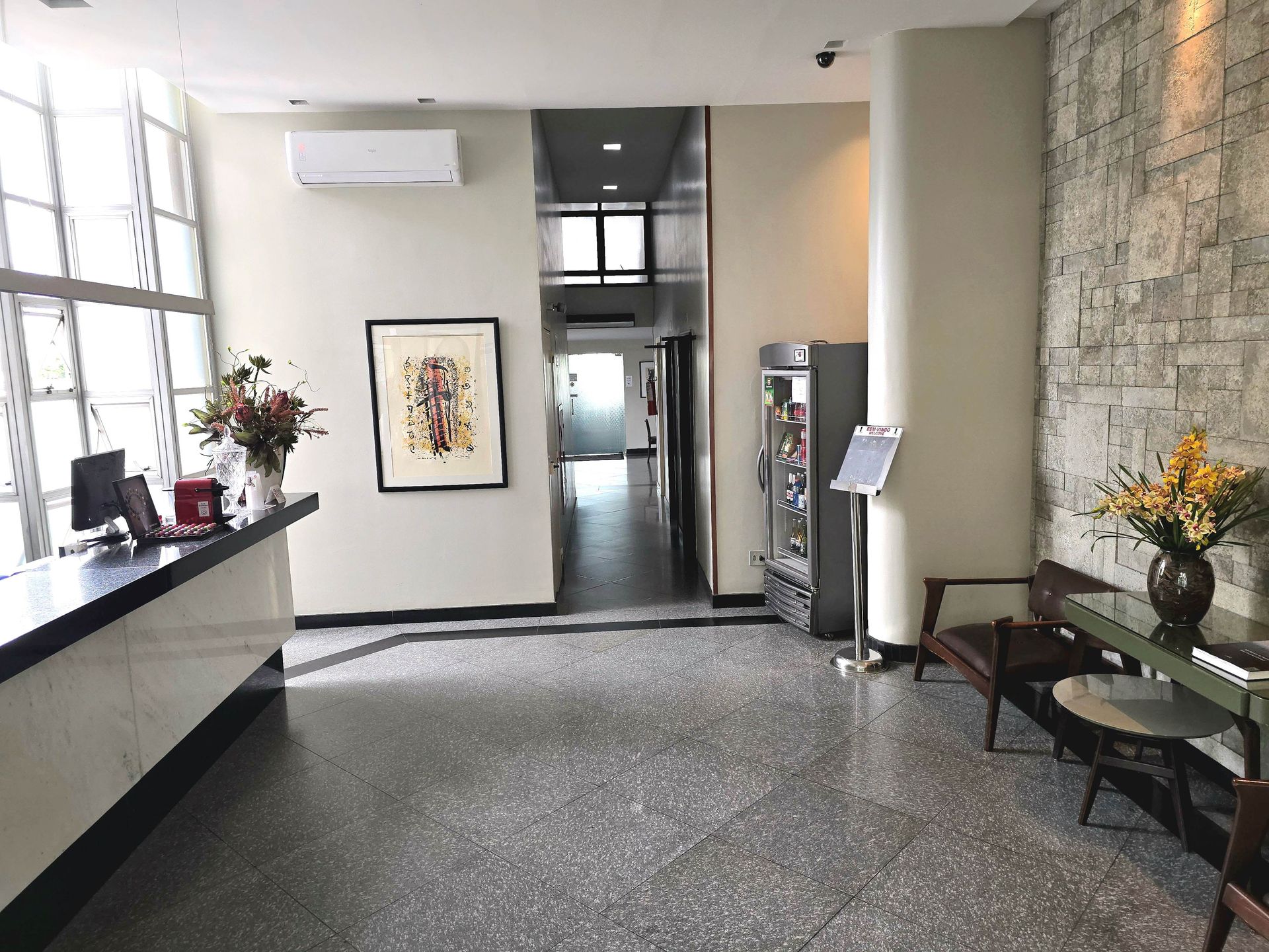 Um lobby com uma mesa, cadeiras, flores e uma pintura na parede.