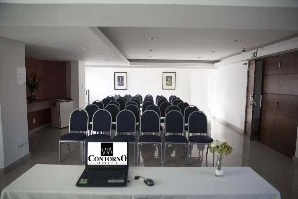 Uma sala de conferências com fileiras de cadeiras e um laptop que diz contorno