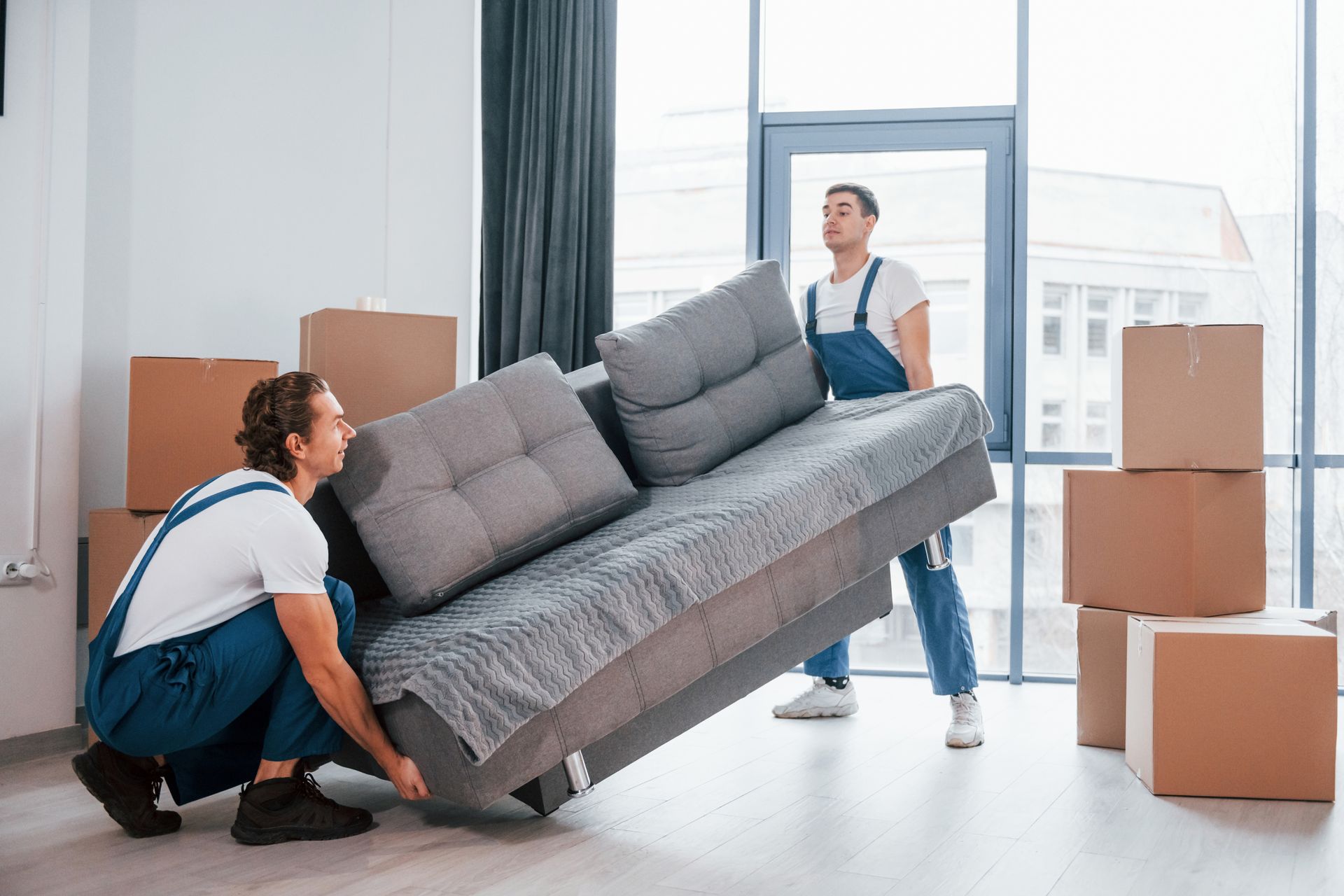 Two experienced movers handling heavy furniture in apartment during professional moving service