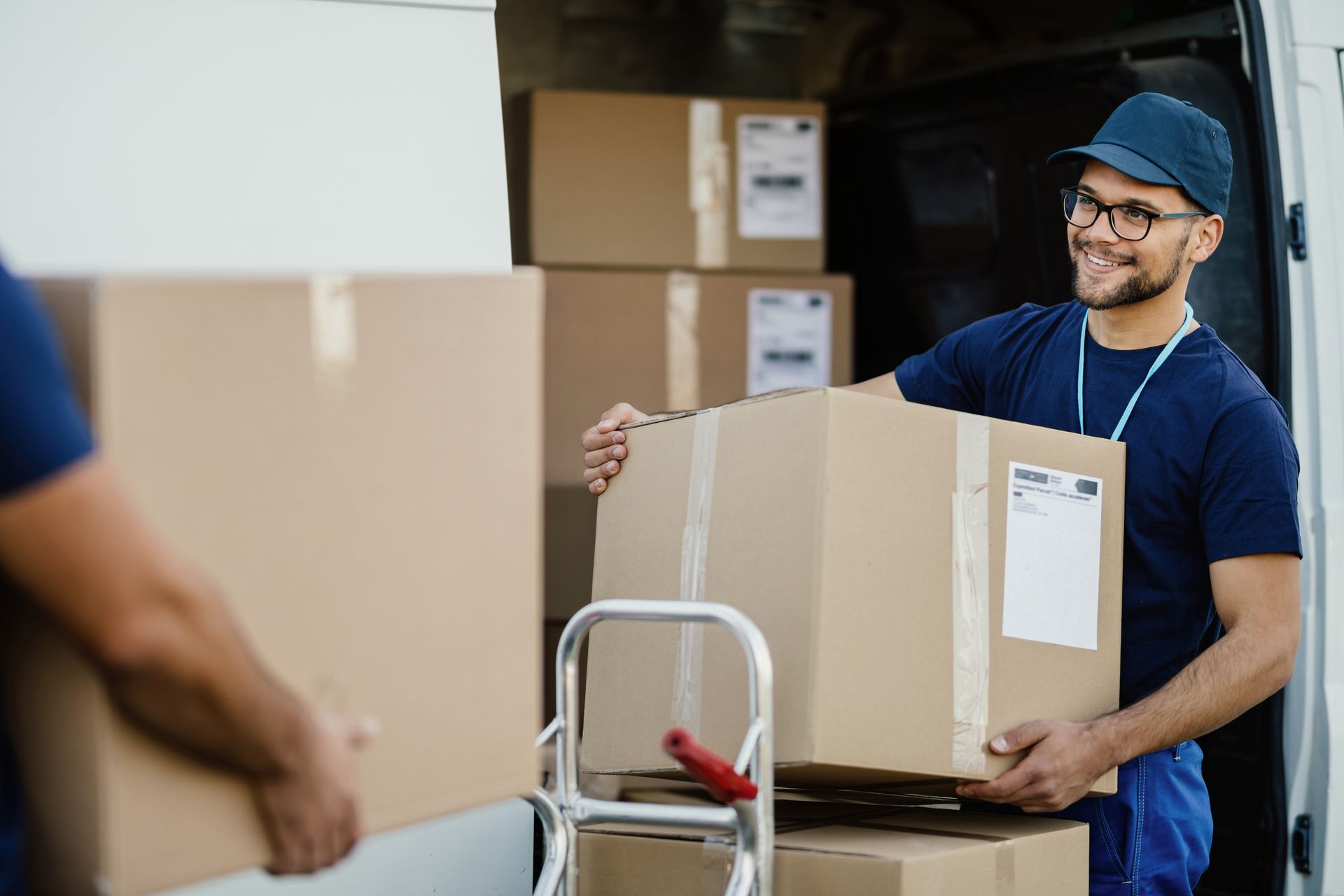 A delivery man is carrying a cardboard box out of a van.