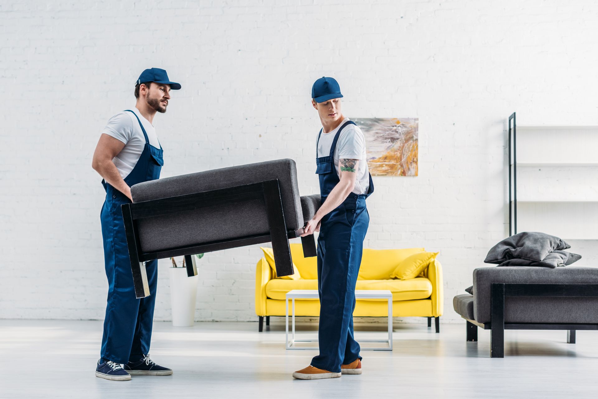 Two movers are carrying a couch in a living room.