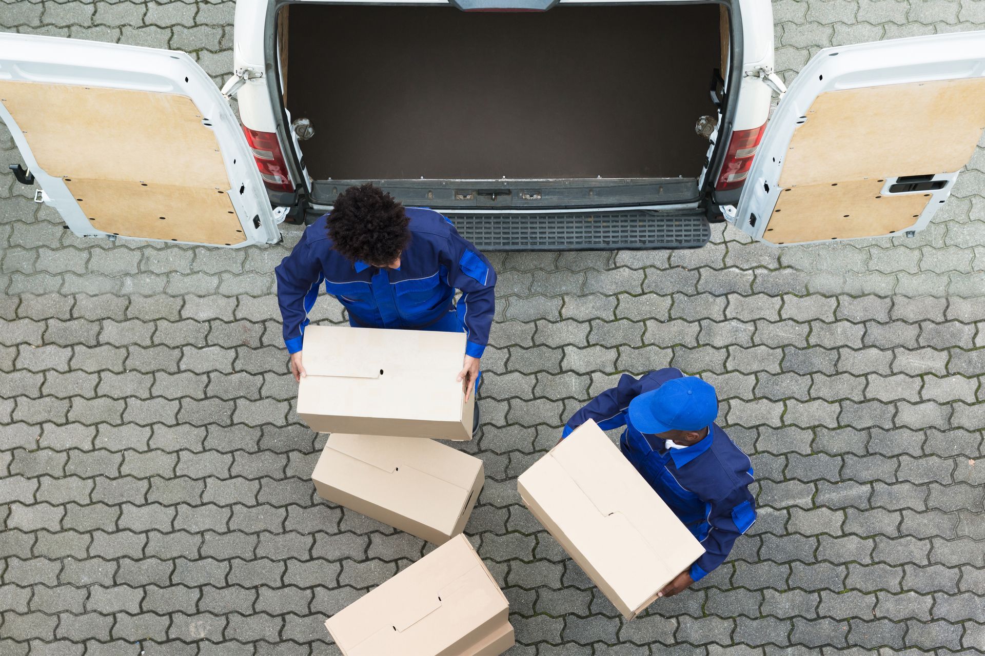 Two delivery men are loading boxes into the back of a van.