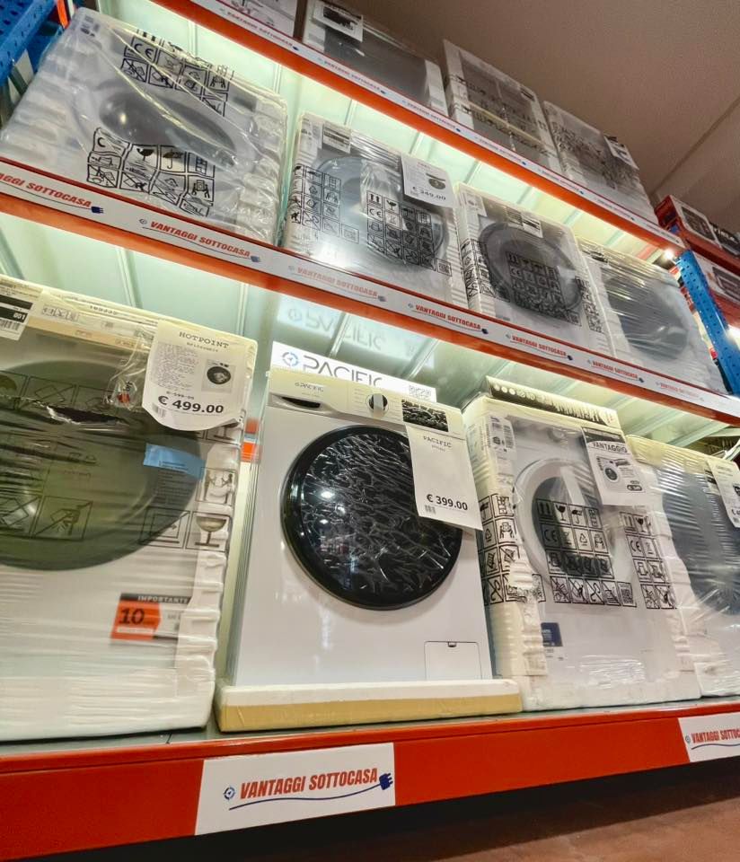 Lavatrici in vendita sugli scaffali di un negozio al dettaglio, modelli bianchi con grandi sportelli circolari e cartellini del prezzo.