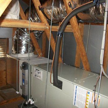HVAC system in an attic; ductwork, insulation, and wooden rafters are visible.