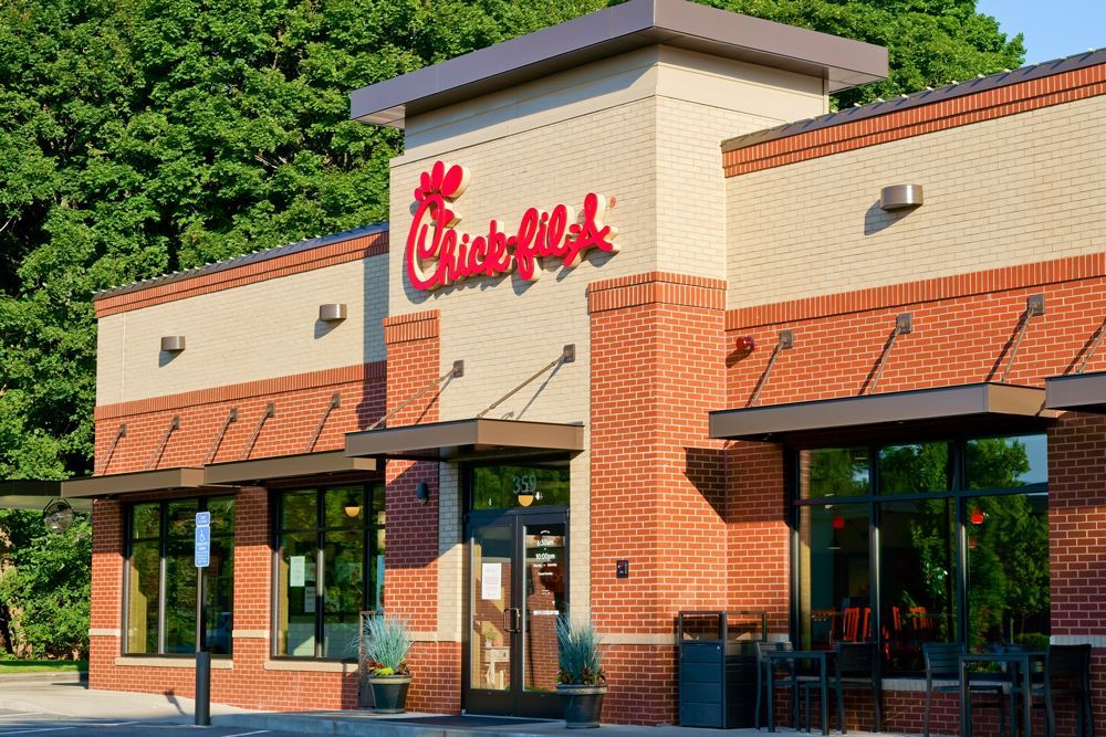 A chick-fil-a restaurant with a brick building and a red sign on the side.