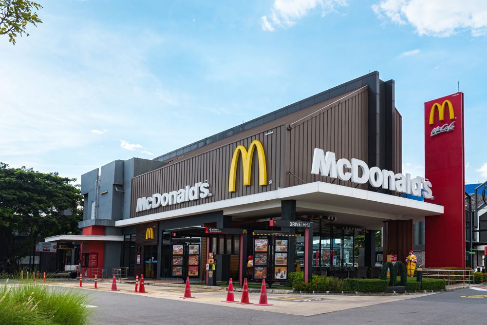 The outside of a mcdonald 's restaurant with a blue sky in the background.