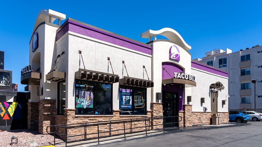 A taco bell restaurant with a purple awning on the side of it.