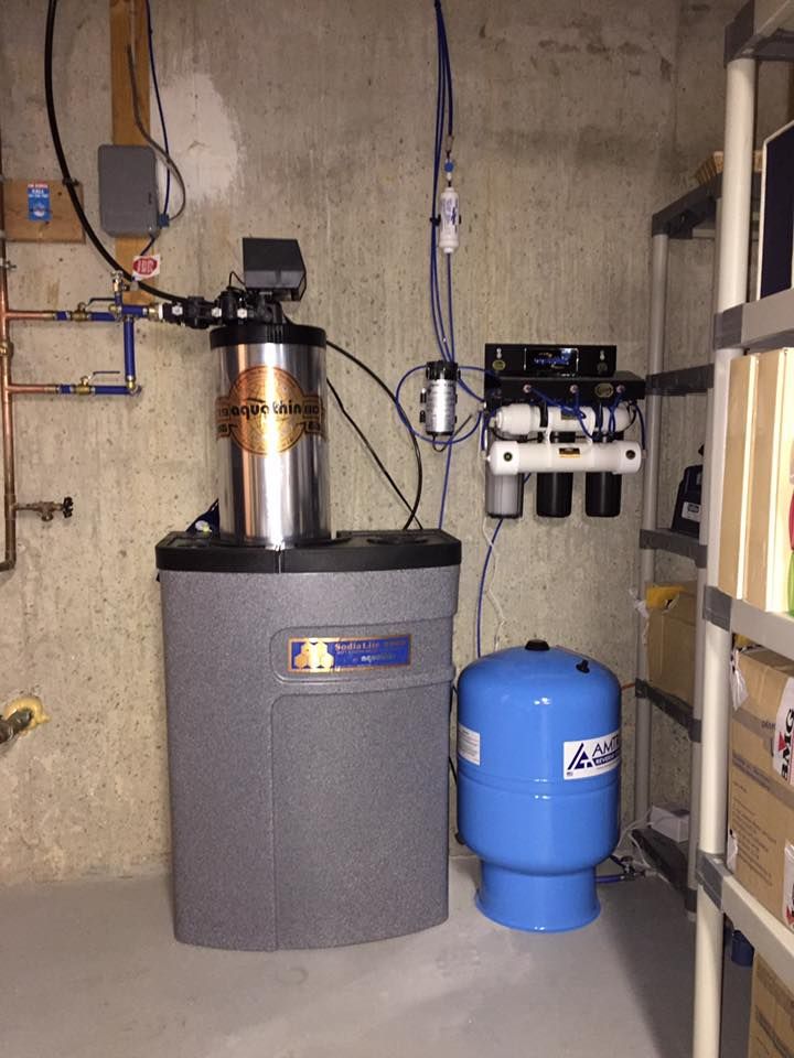 Water filtration system with tank, blue pressure tank, and shelving in a basement.