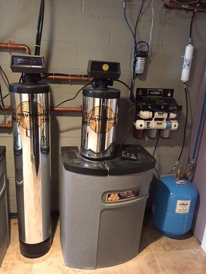 Water filtration and softening system in a basement setting. Includes tanks, filters, and control panels.
