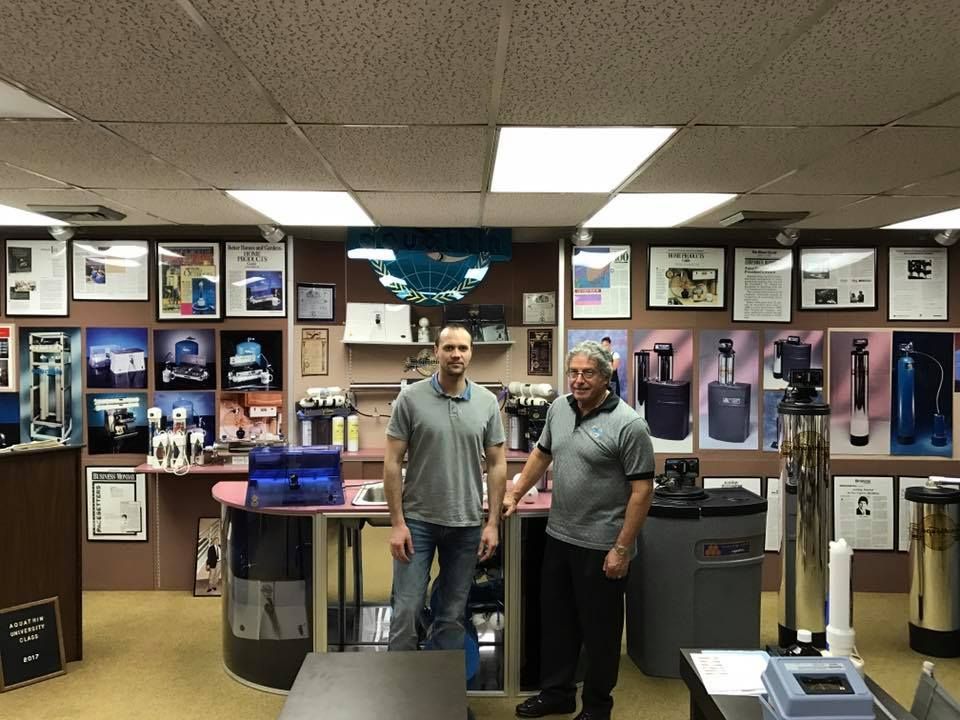 Two men in a water filtration store, standing in front of display models.