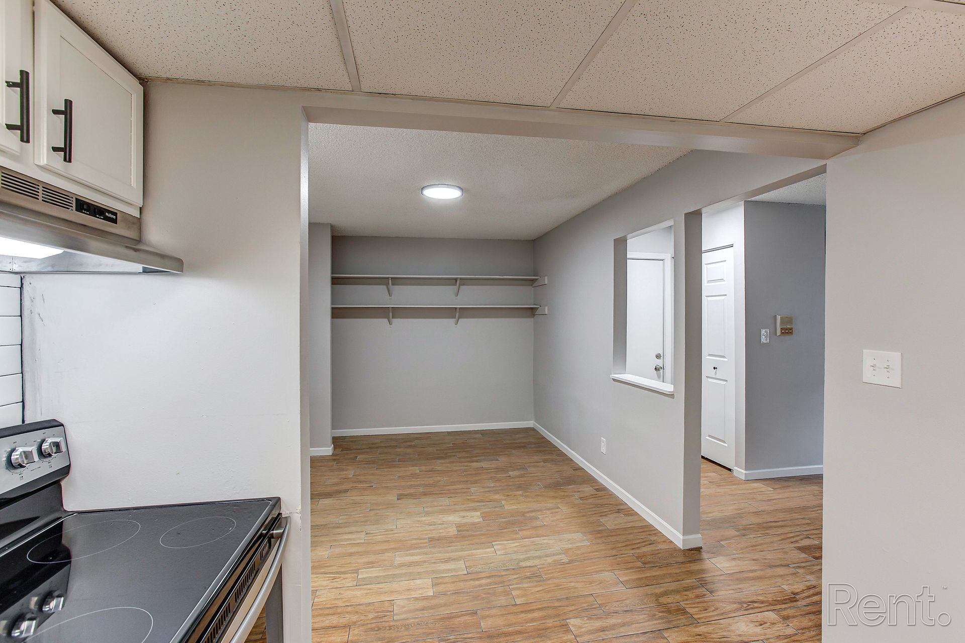 Kitchen with cabinets, stove, opening to a dining area and storage shelves.