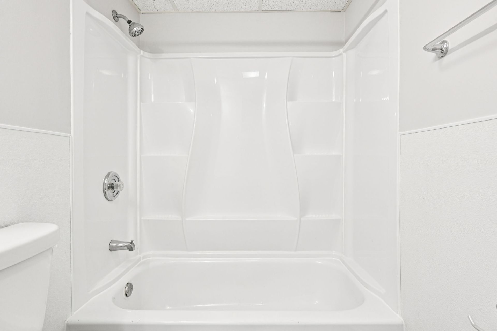 White, clean bathroom with a shower/tub combo and toilet.
