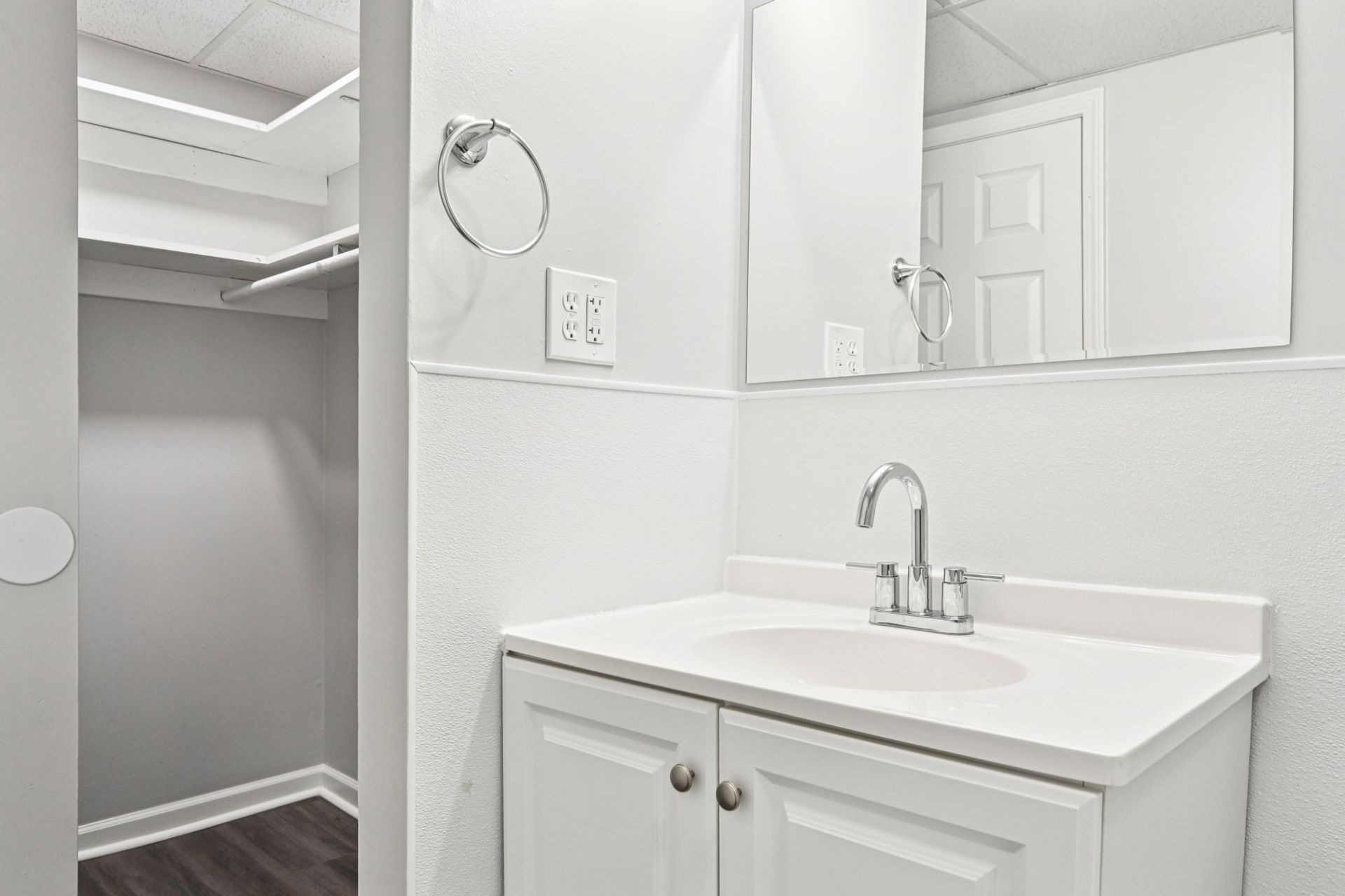 Small white bathroom with a sink, mirror, and closet.