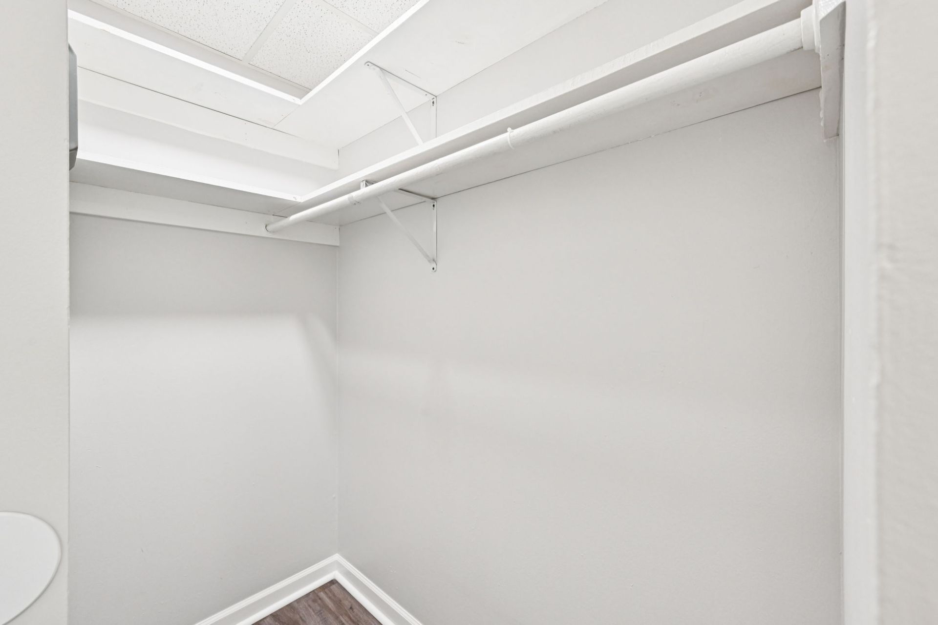 Empty white closet with shelves and a rod.