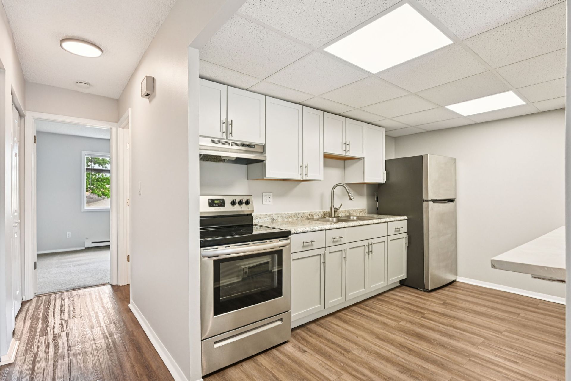 Kitchen with white cabinets, stainless steel appliances, and wood-look flooring.
