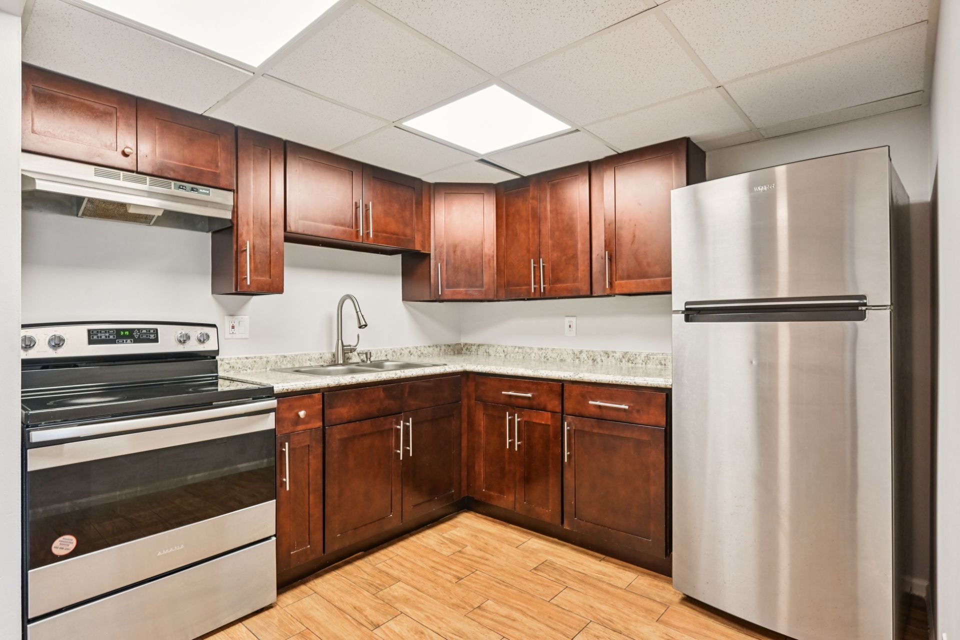 Kitchen with dark wood cabinets, stainless steel appliances, and light countertops.