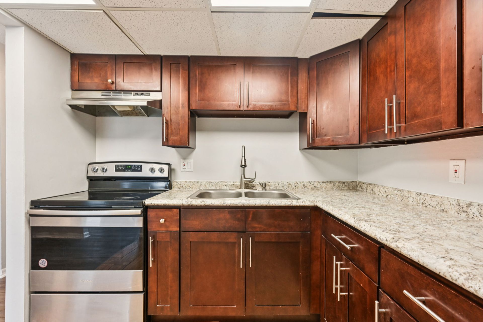Kitchen with dark wood cabinets, stainless steel appliances, and granite countertops.