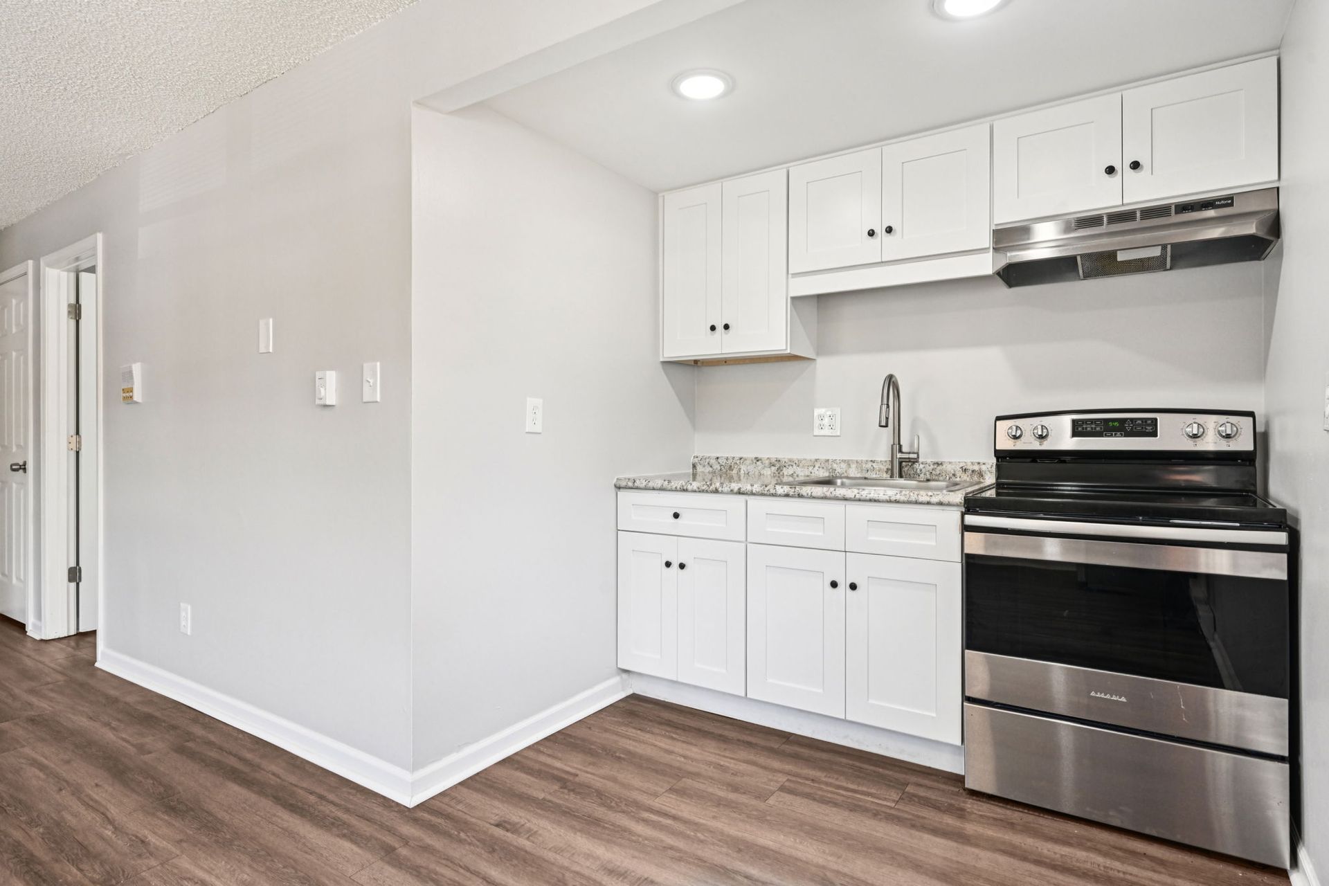 Small kitchen with white cabinets, stainless steel appliances, and gray countertop.