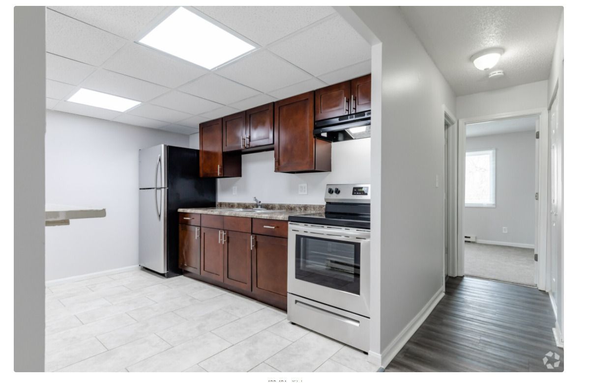 Kitchen with dark wood cabinets, stainless steel appliances, gray walls, and tiled floor.