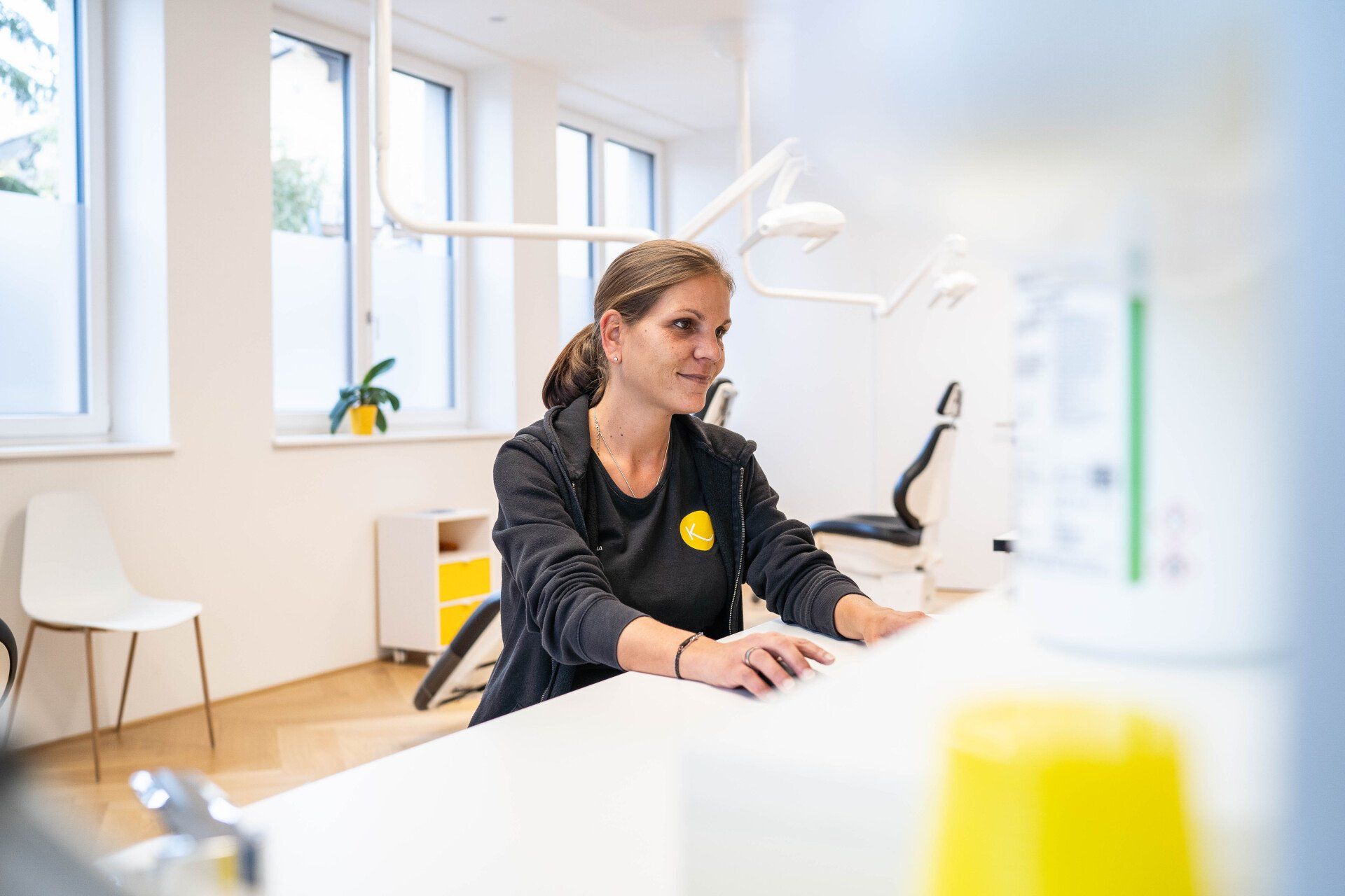 Eine Mitarbeiterin sitzt an ihrem Schreibtisch in der Zahnarztpraxis.