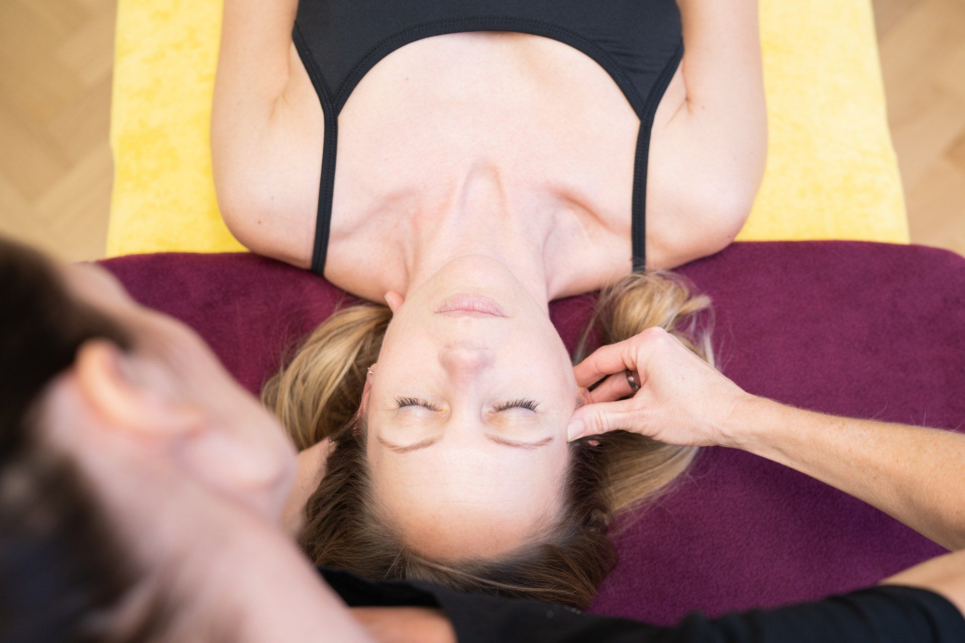 Eine Frau im schwarzen Tanktop bekommt Physiotherapie.