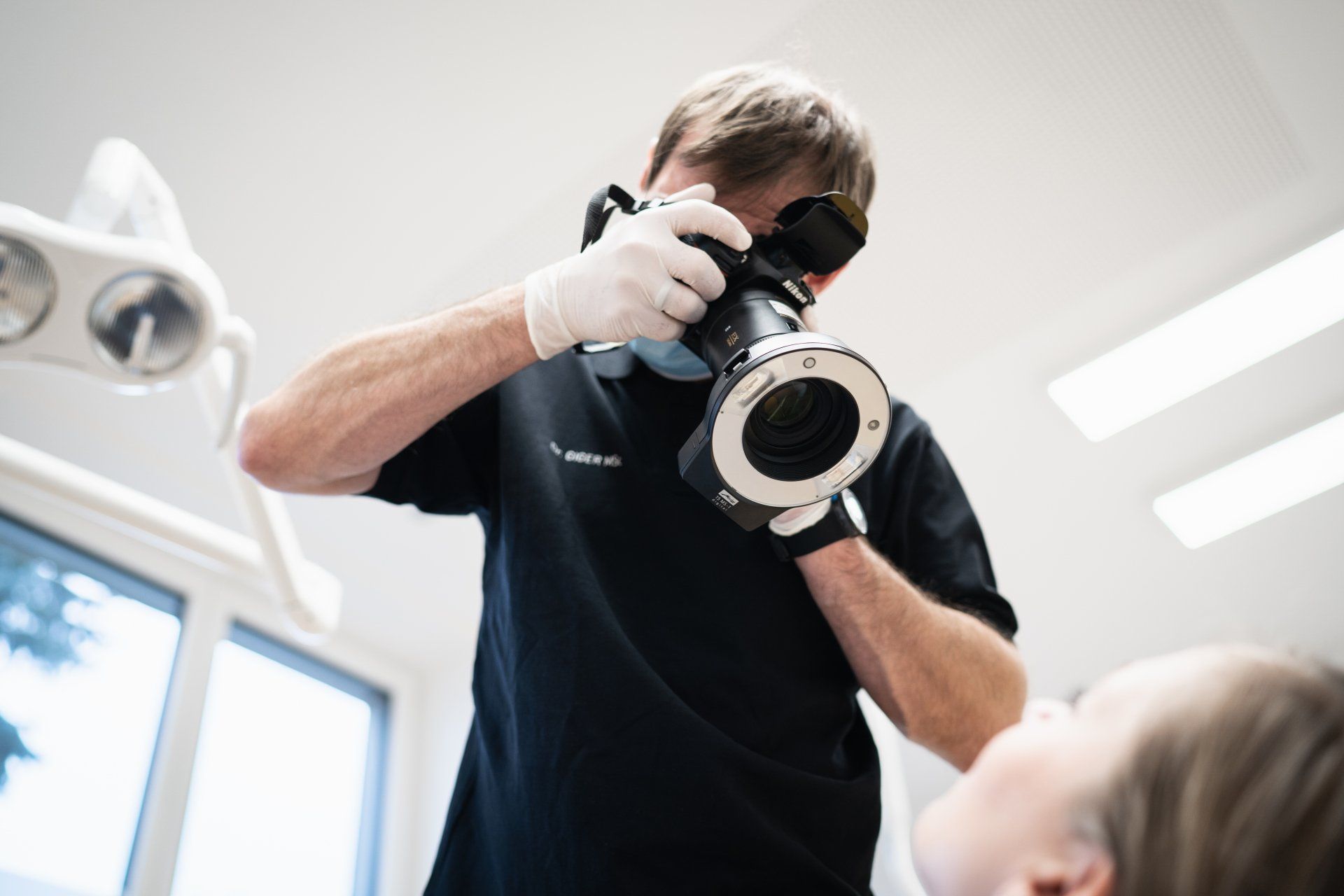 Dr. Hartmut Giger, MSc macht ein Foto von den Zähnen eines Patienten.
