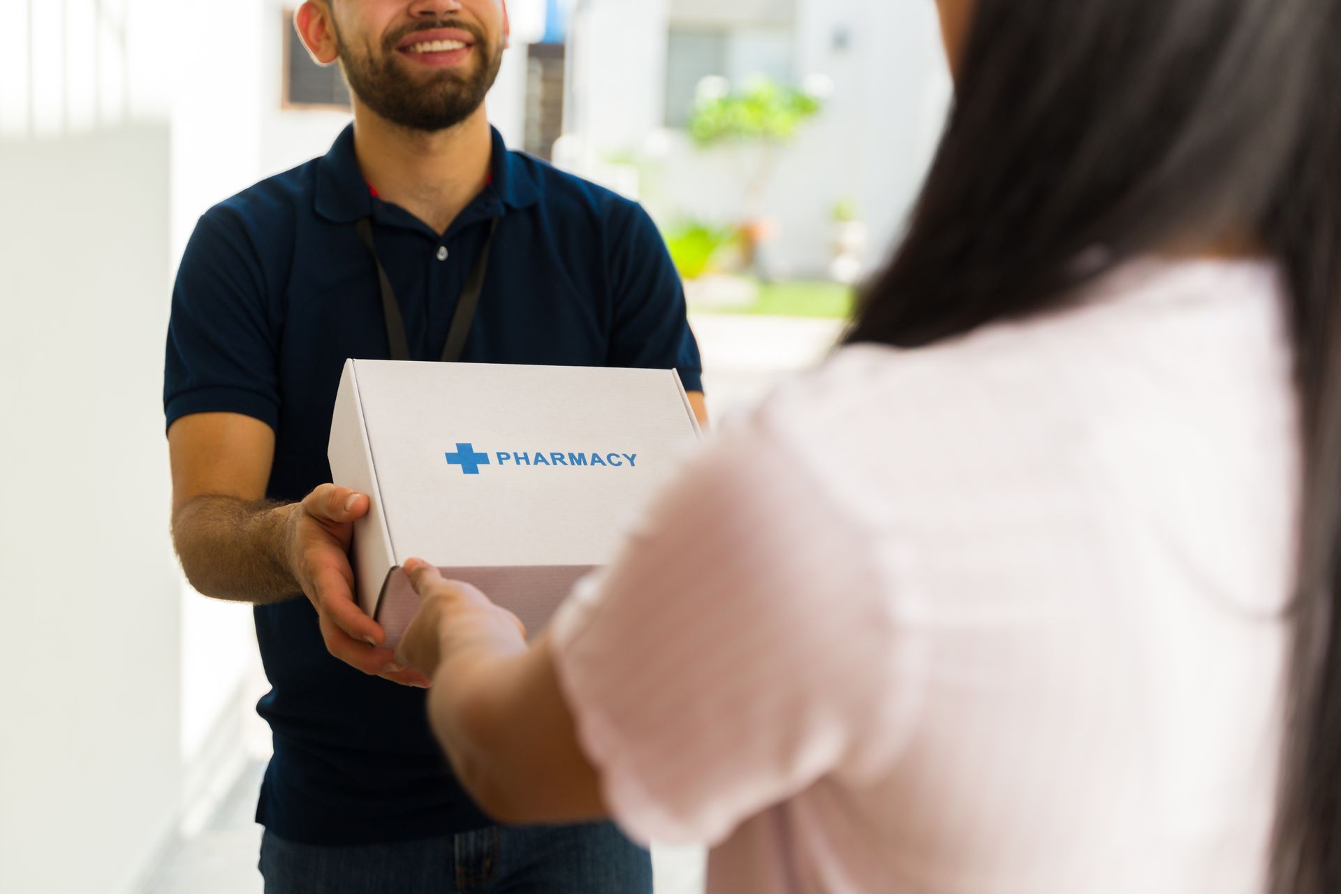 Courier handing a pharmacy delivery box to a customer at the door. Courier handing a pharmacy delivery box to a customer at the door.