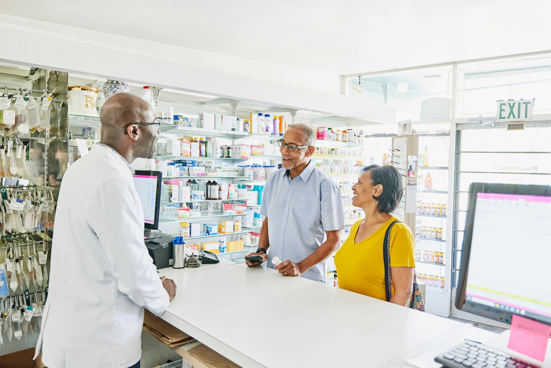 Smiling senior couple picking up prescription at counter in pharmacy.